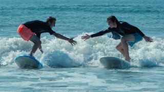 Two surfers give each other a high five on a wave near our Wildwood Crest NJ hotel