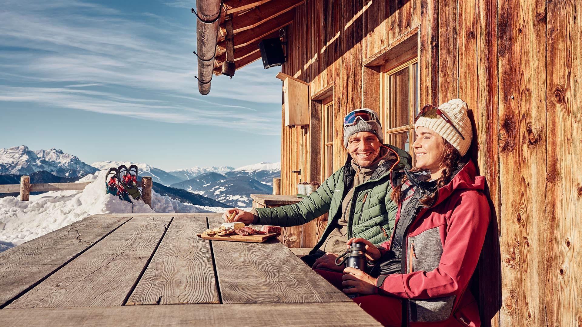 Couple enjoying a sunny day on the deck of a wooden cabin at Falkensteiner Hotels & Residences