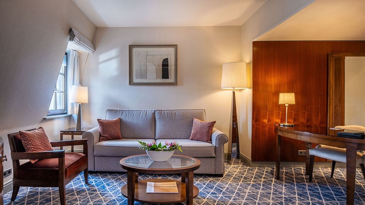 Junior Suite living area with plush couch and work desk near window at Warwick Grand Place Brussels