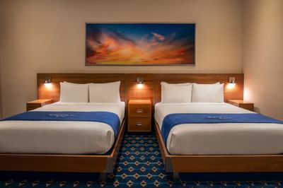 Two queen beds with wall art in Double Queen Atrium at Harborside Inn