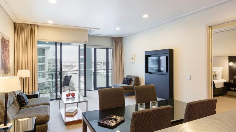 TV lounge and a dining table by the window in the Executive Deluxe One Bedroom Suite at The Sebel Auckland Viaduct Harbour