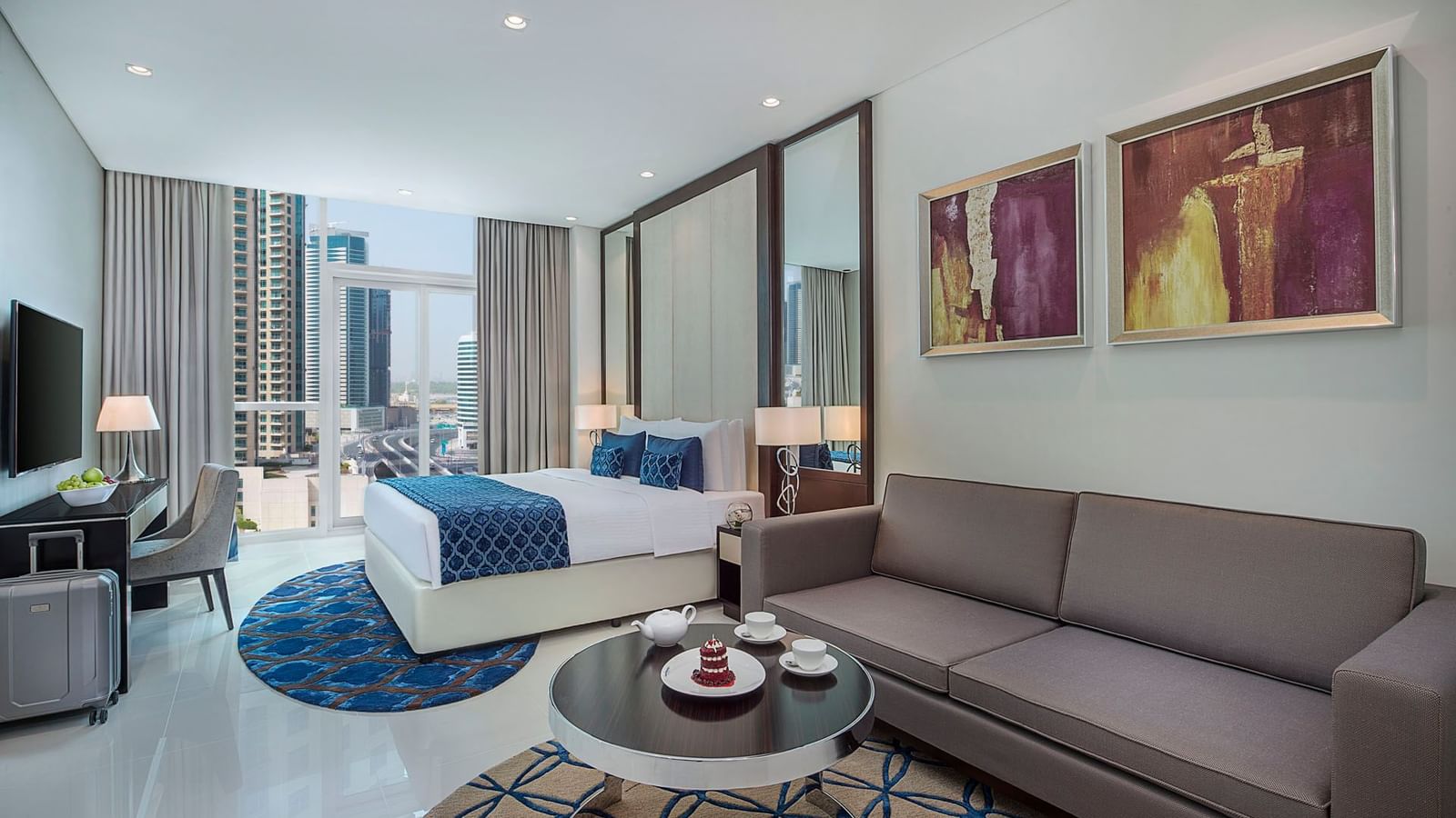 Cozy couch with a teapoy with king-size bed by the window in Deluxe Room at DAMAC Maison Distinction