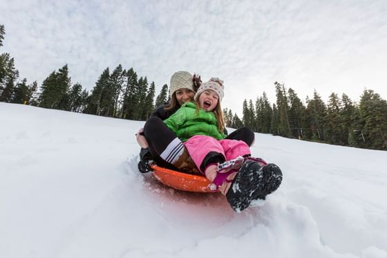 two people in a toboggon sled riding down Granlibakken's sledding hill