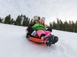 Mom & kid sledding on snow at Granlibakken Tahoe