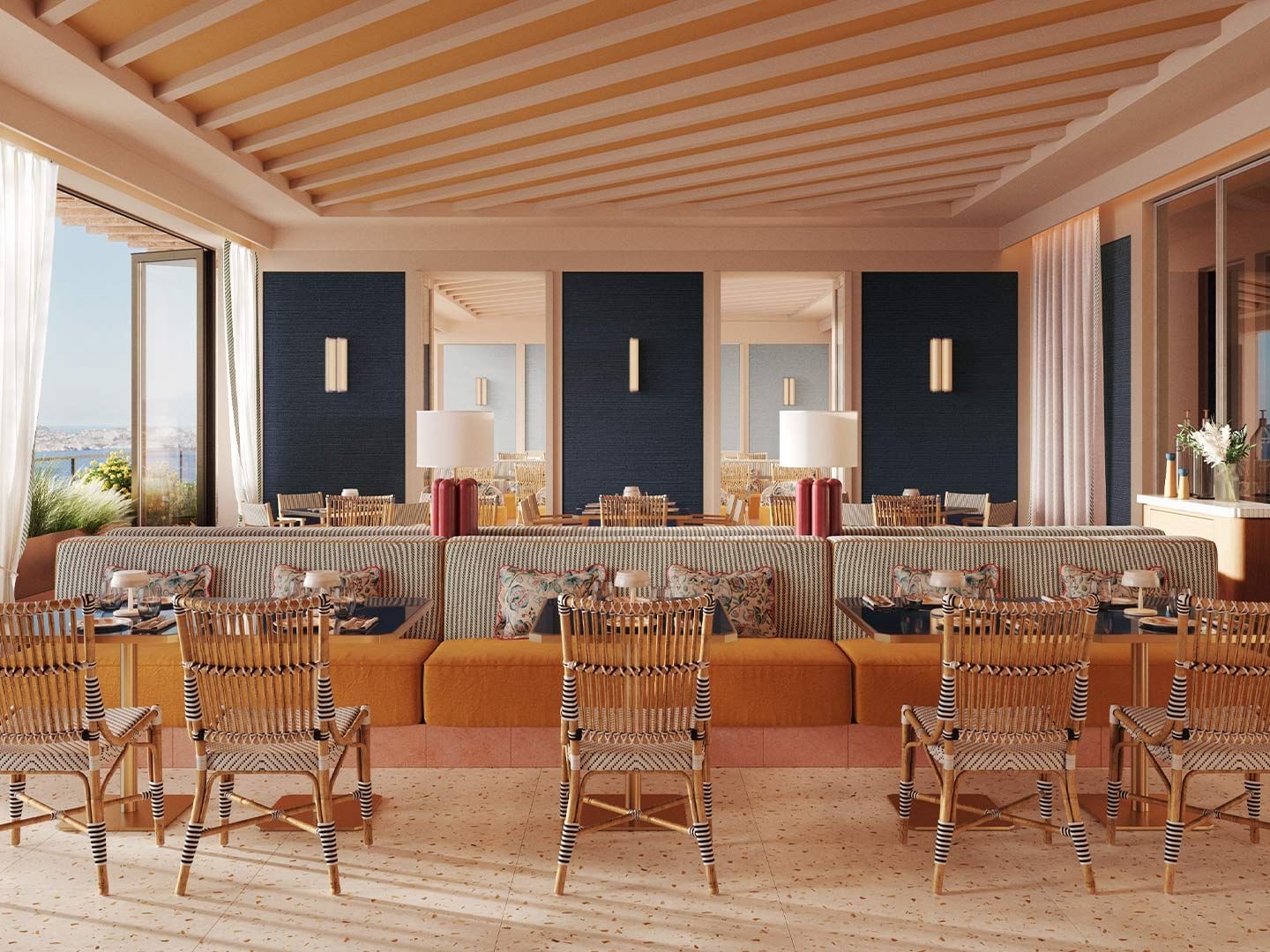 A modern restaurant with a large couch, several chairs, and glass walls with ocean view.