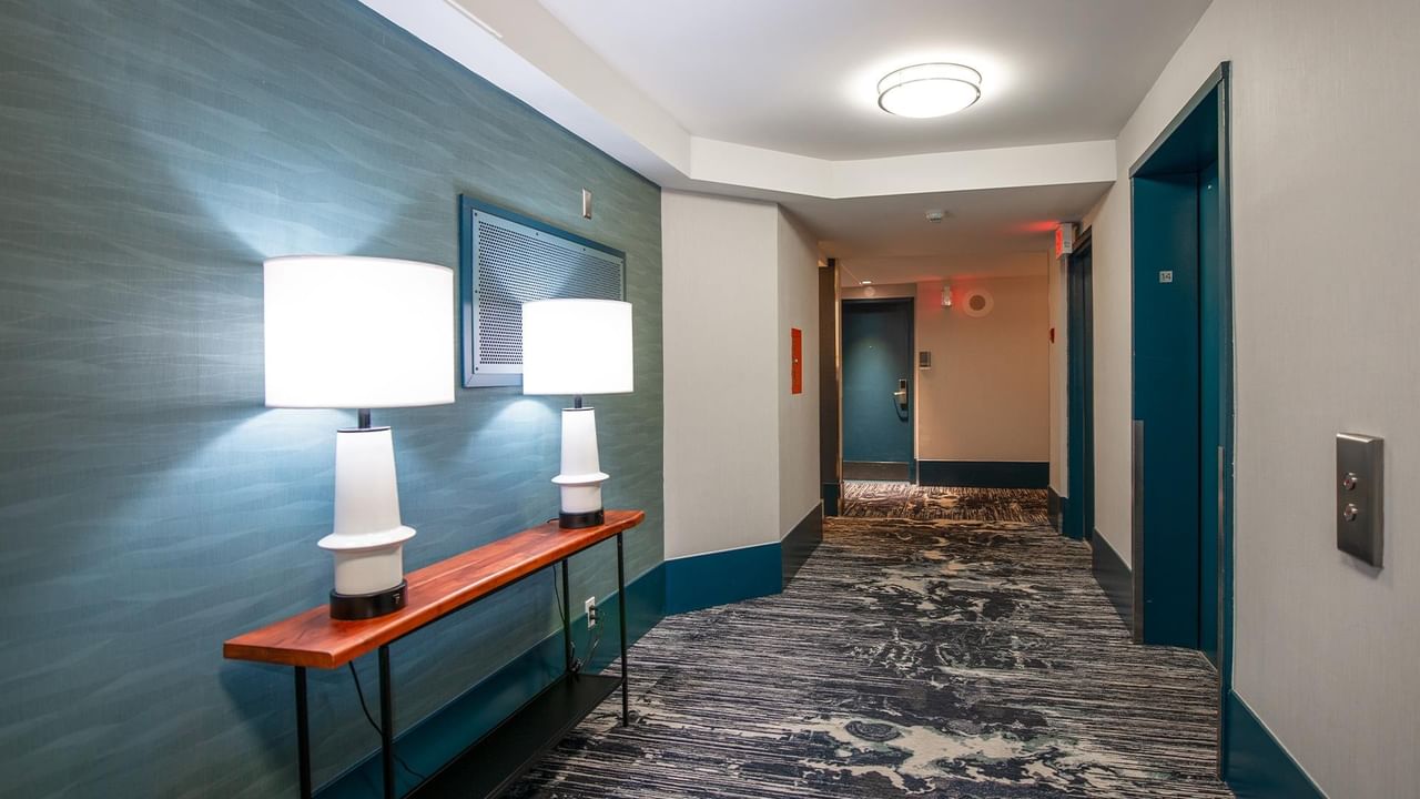 Long corridor with blue walls, lamps, and carpeted floor at Coast Bastion Hotel.