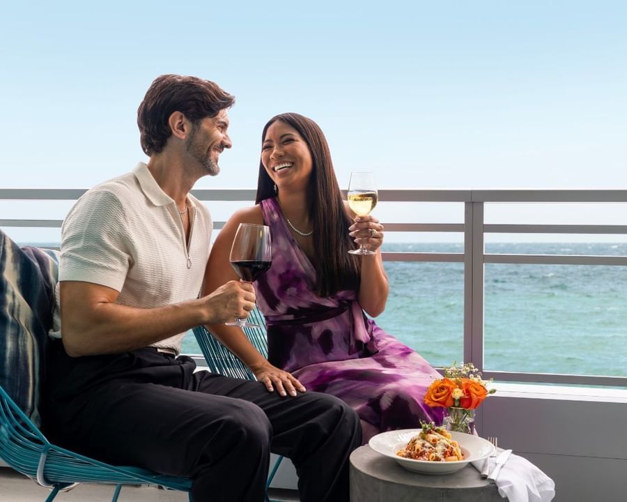 Couple enjoying drinks & sharing a meal in the balcony overlooking the sea at The Diplomat Resort