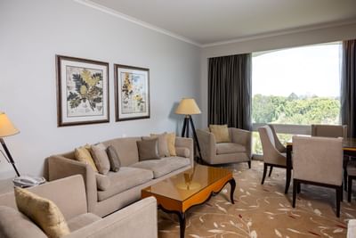 An elegant hotel suite living room with a sofa and dining area at the Royal on the Park Hotel