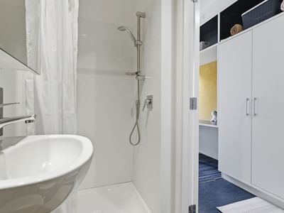 Modern bathroom with a shower, sink, and white cabinets at UniLodge Auckland City.