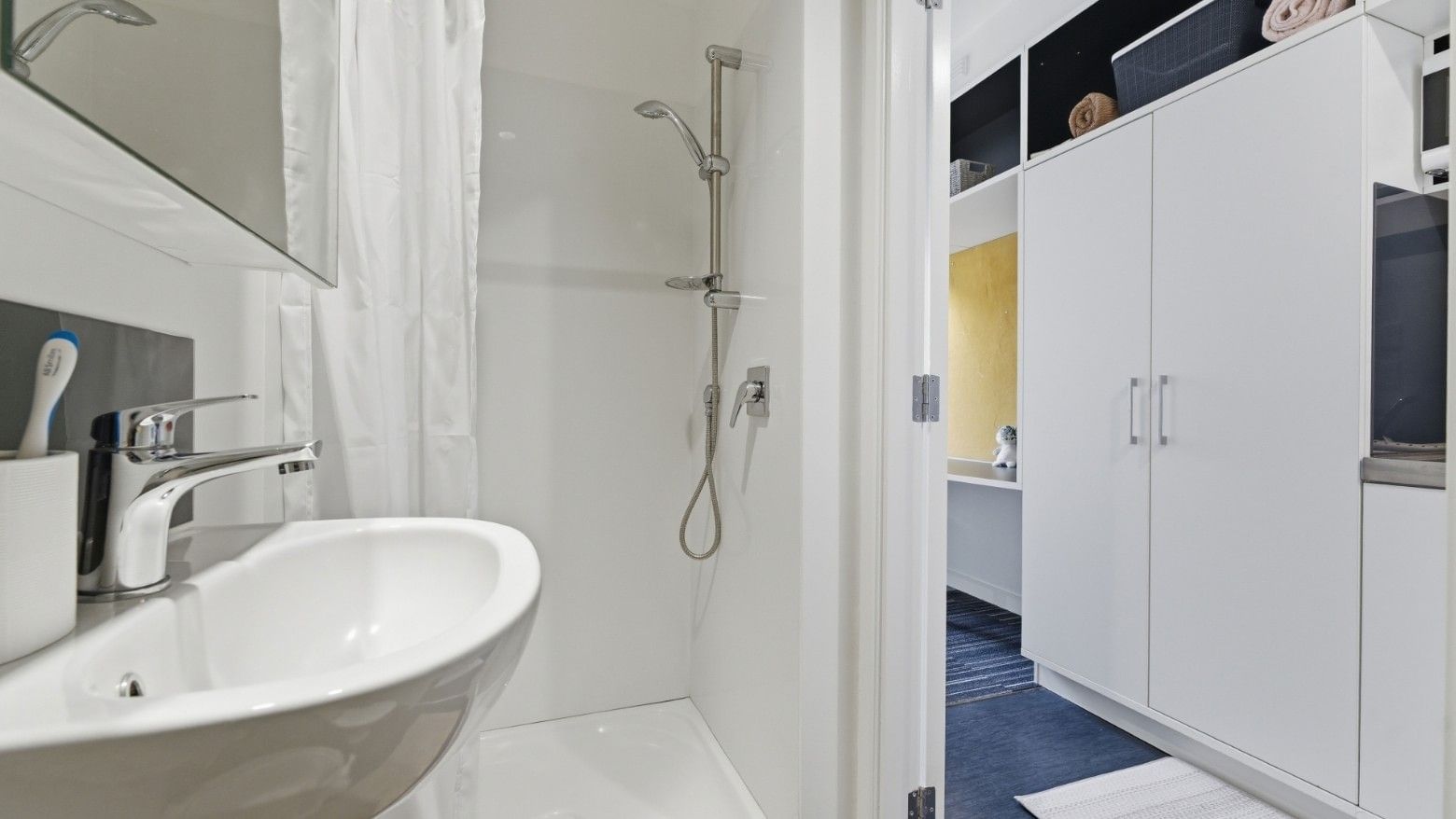 Modern bathroom with a shower, sink, and white cabinets at UniLodge Auckland City.