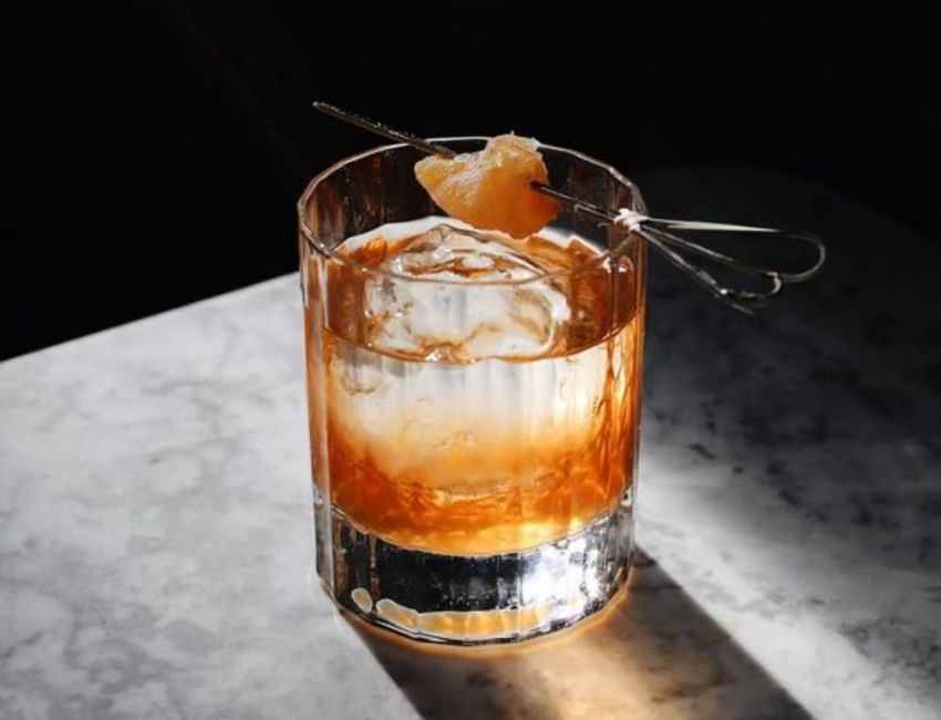 Glass of whiskey with ice and garnish at Paradox Vancouver
