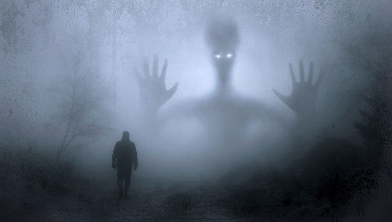 Scary shadowy figure cast over man walking in foggy forest