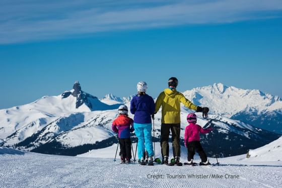 A family with skiing gear & winter clothes on a snow hill near Blackcomb Springs Suites