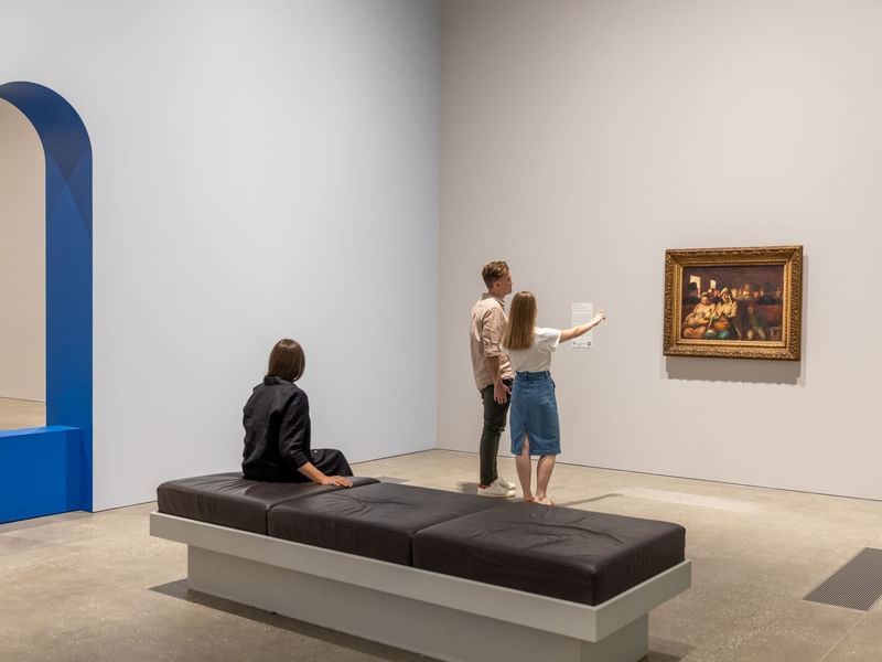 Two individuals exploring a framed painting in QAGOMA near Sofitel Brisbane Central
