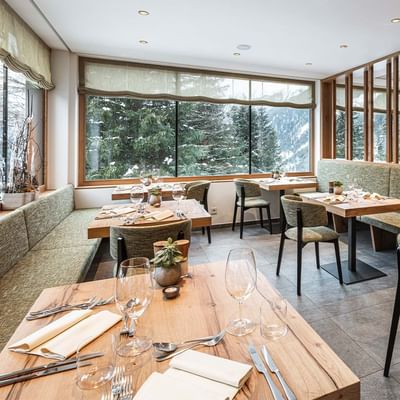 Dining tables and chairs arranged in a restaurant at Falkensteiner Hotel Antholz