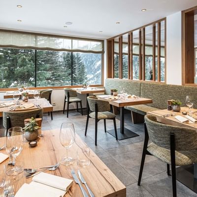 Dining tables and chairs arranged in a restaurant at Falkensteiner Hotel Antholz