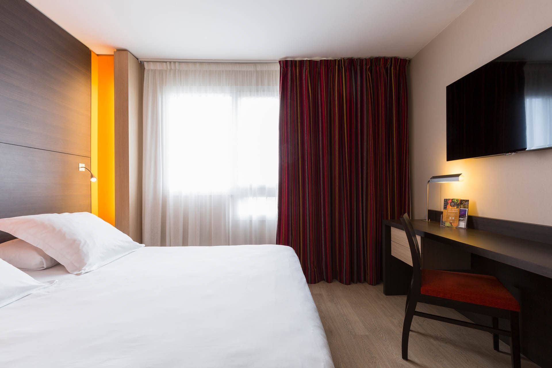 King bed, TV & Desk in a room at Oceania Nantes Aéroport