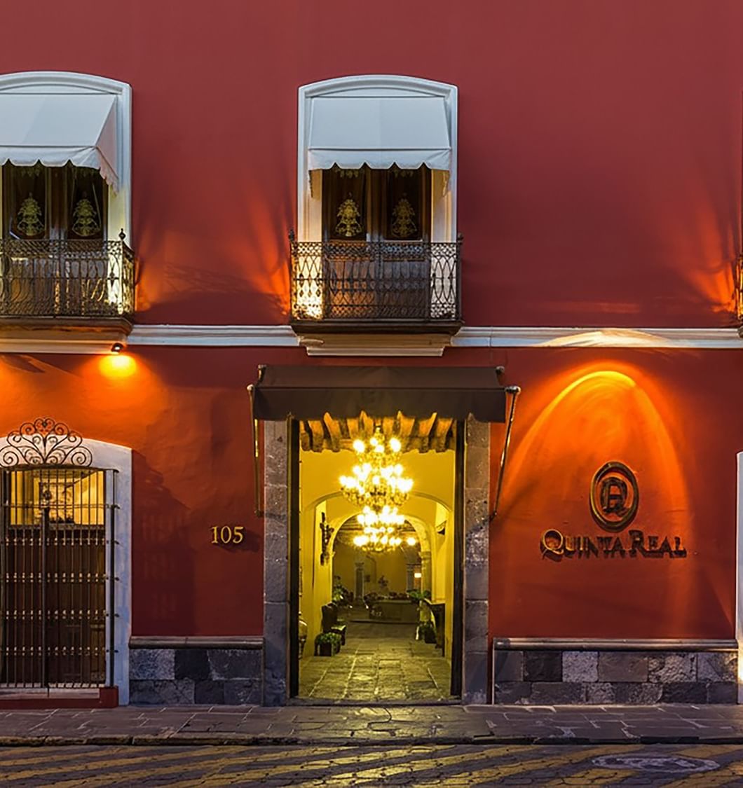 Fachada de hotel estilo colonial con balcones decorativos y entrada principal majestuosa en Quinta Real Puebla