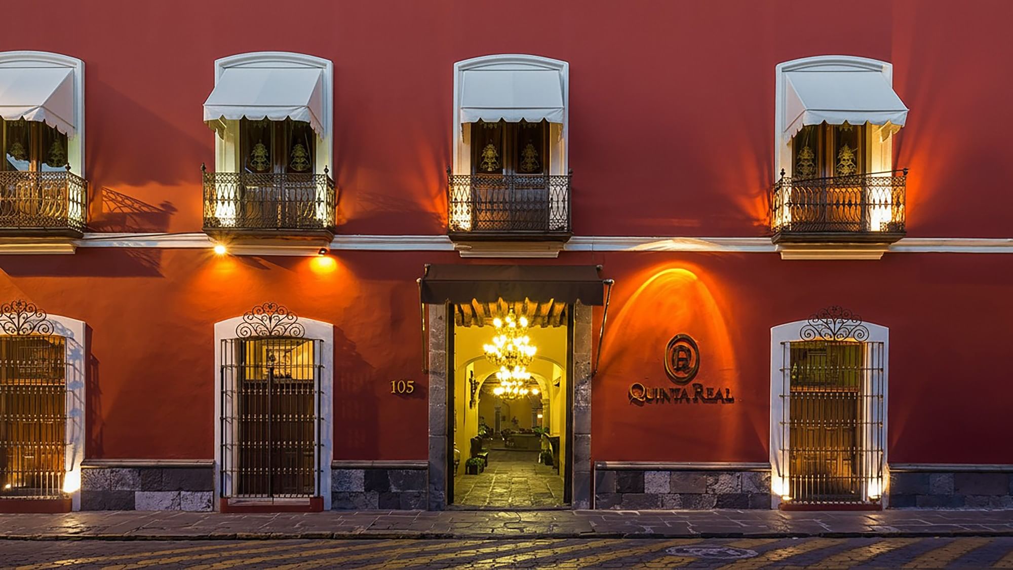 Fachada de hotel estilo colonial con balcones decorativos y entrada principal majestuosa en Quinta Real Puebla