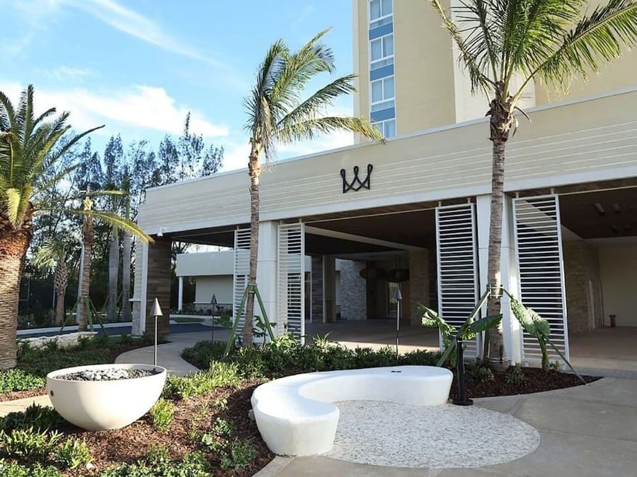 White curved bench by a fire pit under palm trees surrounding the entrance at Warwick Paradise Island Bahamas