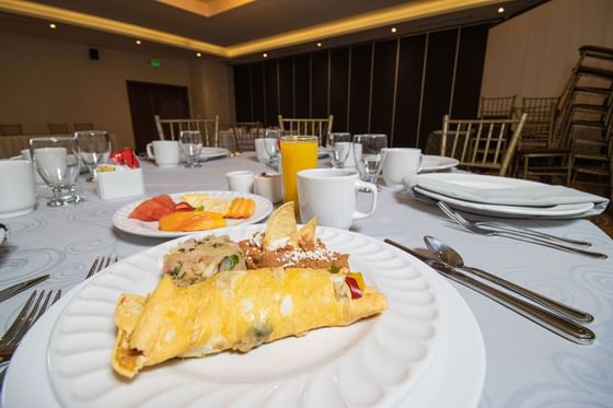 Mesa de banquete elegante con manteles blancos, platos, servilletas dobladas y comidas en Araiza Calafia