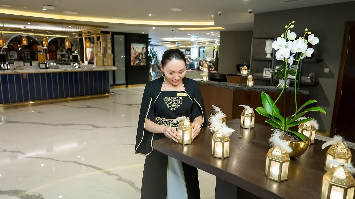 A lady standing the lanterns on a table in The Stage Restaurant at Paramount Hotel Dubai