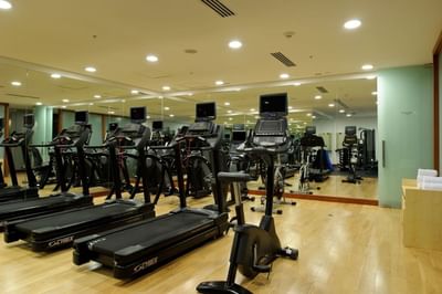Fila de cintas de correr junto a gran espejo bajo luces empotradas brillantes en gimnasio de NOI Vitacura