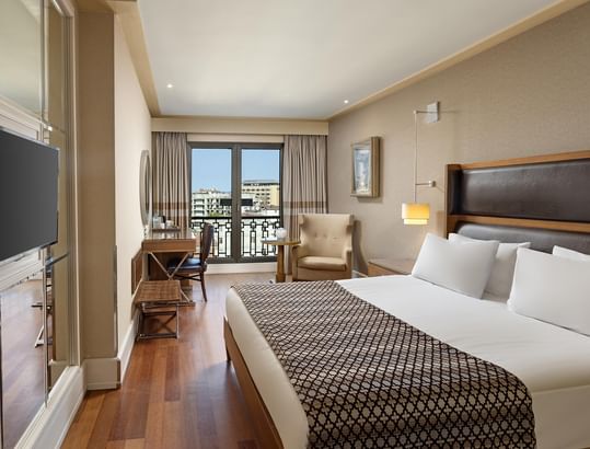 Superior Room at Titanic City Taksim with a large bed, wooden floors, balcony, desk, chair, and a flat-screen TV.