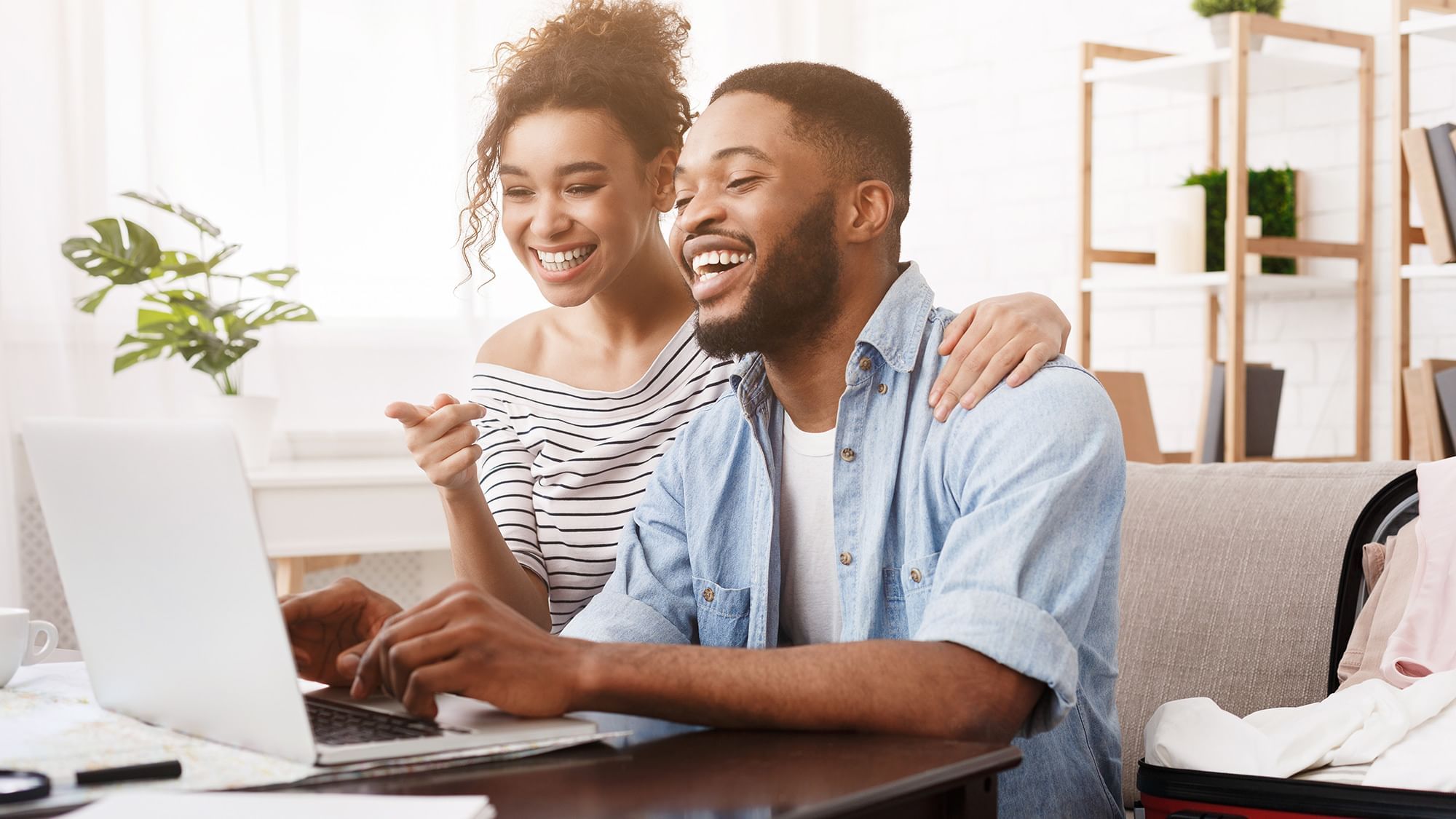 Couple smiling  and pointing while on computer