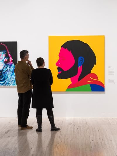 Two people admiring art paintings in Archibald 2026.