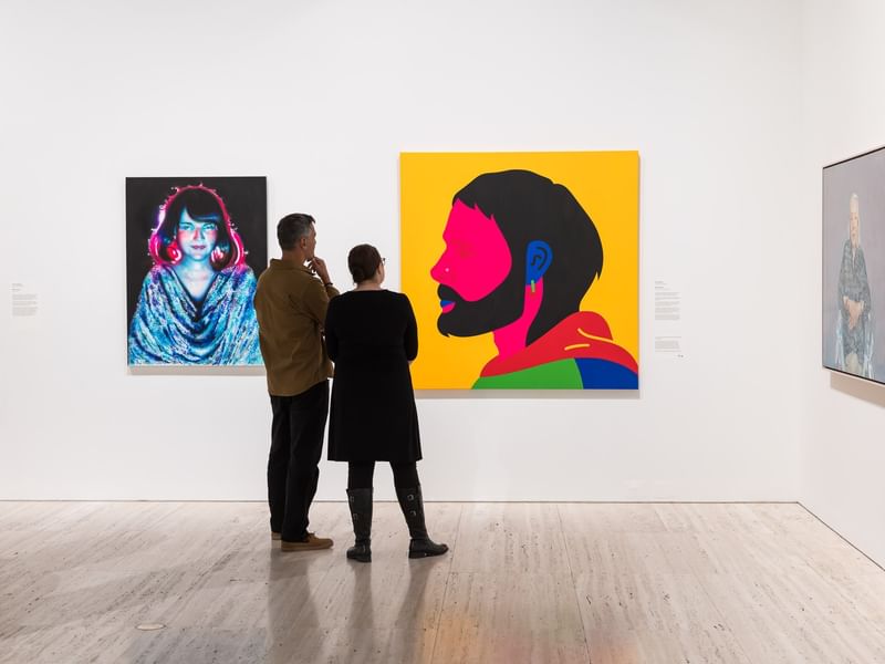 Two people admiring art paintings in Archibald 2026.