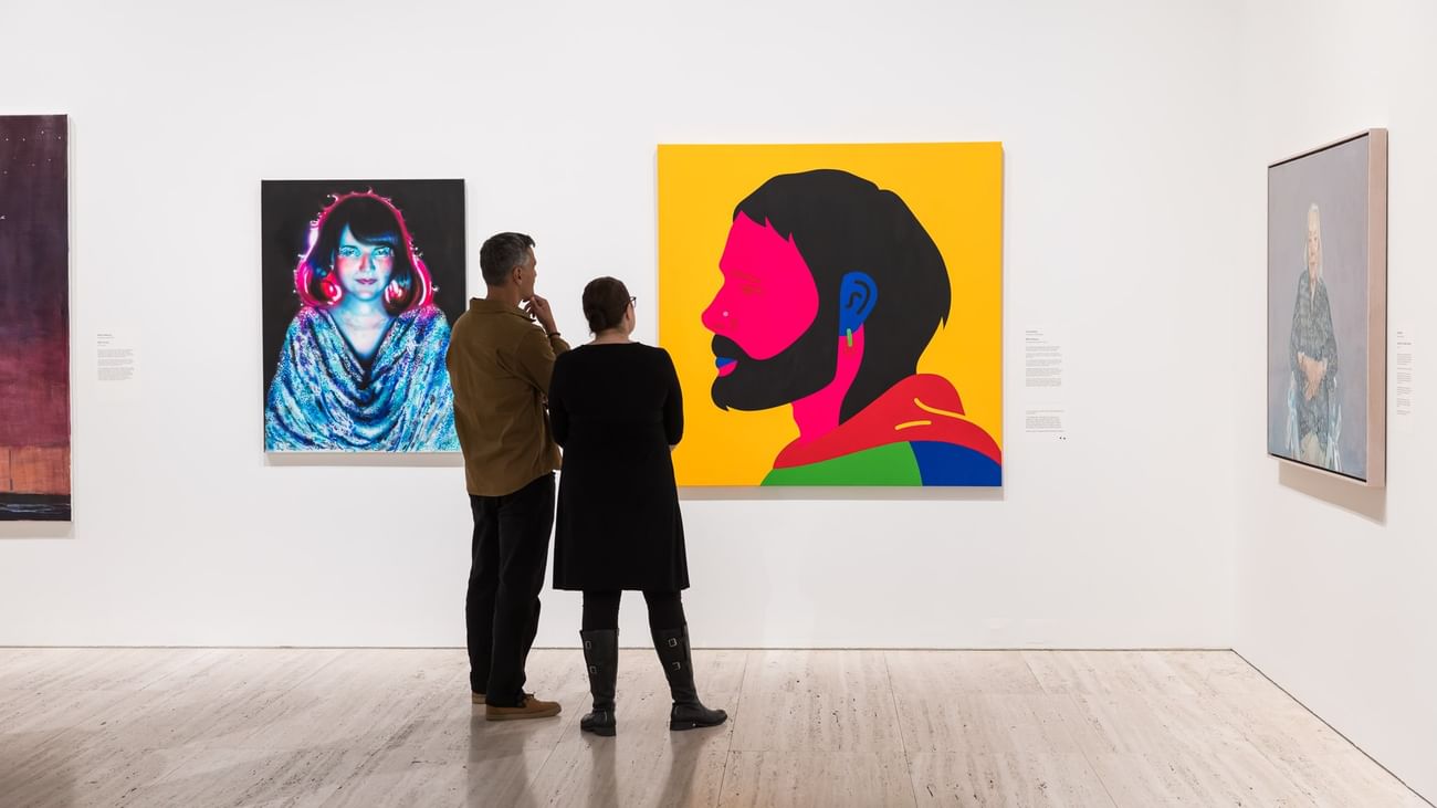 Two people admiring art paintings in Archibald 2026.