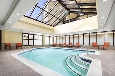 Lounge chairs beside a large indoor pool with a glass roof at Elevation Resort Spa