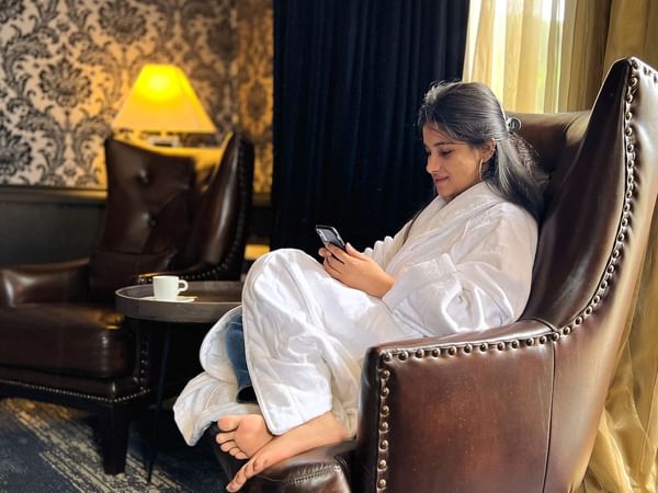 Women using her phone while sitting on a cozy sofa at Midnight Sun, a Coast Hotel