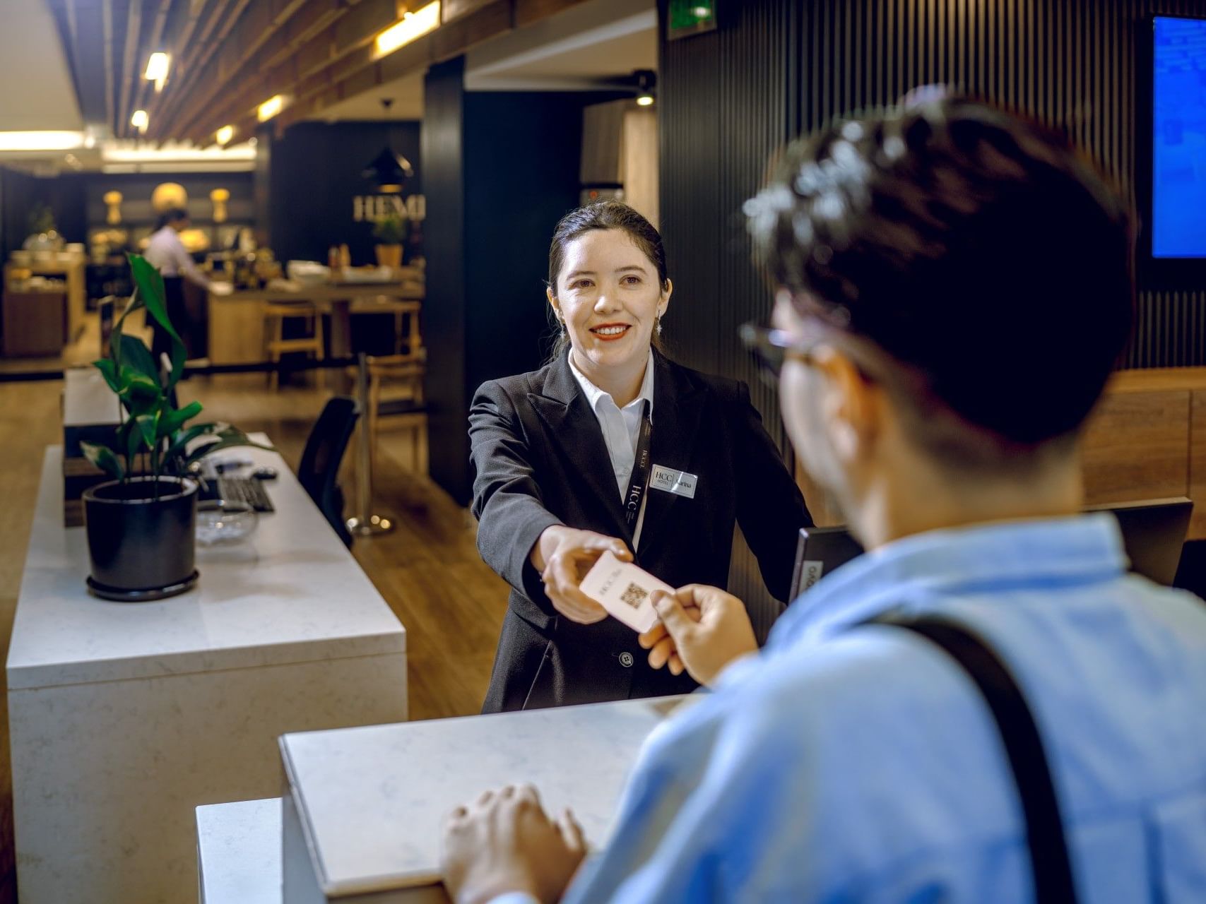 Una recepcionista entregando una tarjeta de acceso a un huésped en la recepción del hotel.