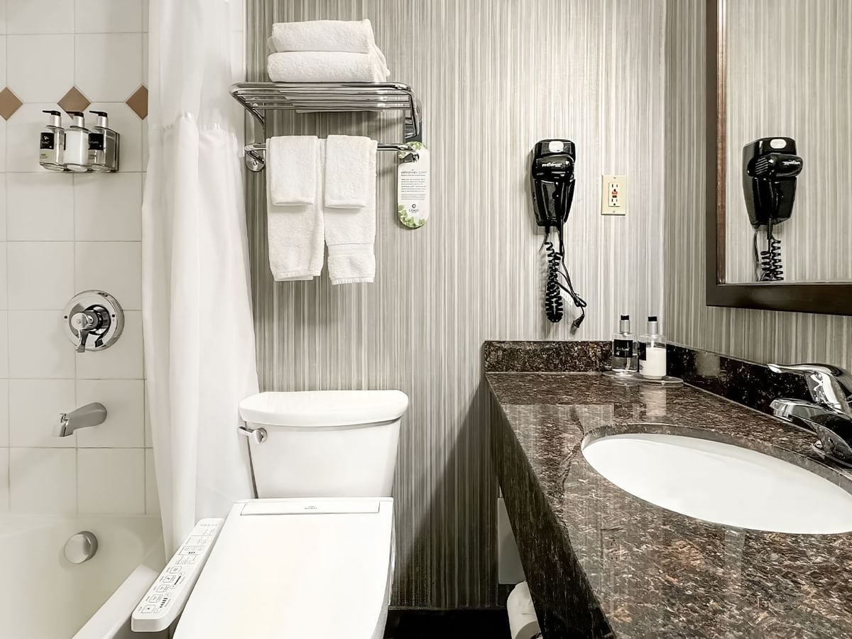 Hotel washroom with toilet, bathtub, soap and towels