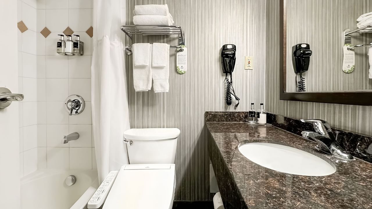 Hotel washroom with toilet, bathtub, soap and towels