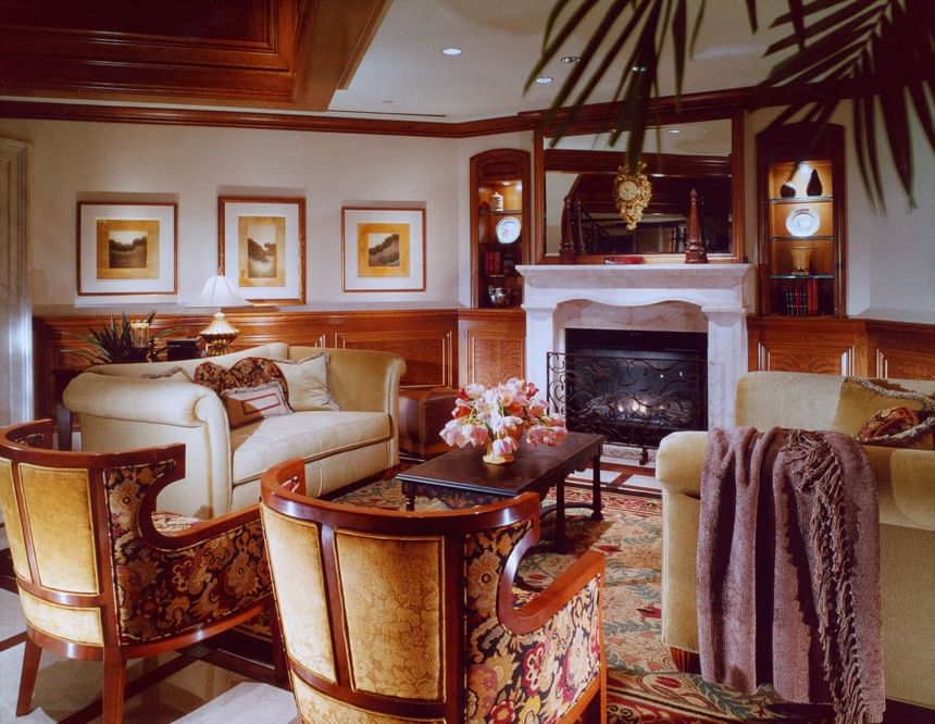 Cozy living room featuring elegant furniture, a fireplace, decorative artwork, and warm wood accents at The Rose Hotel