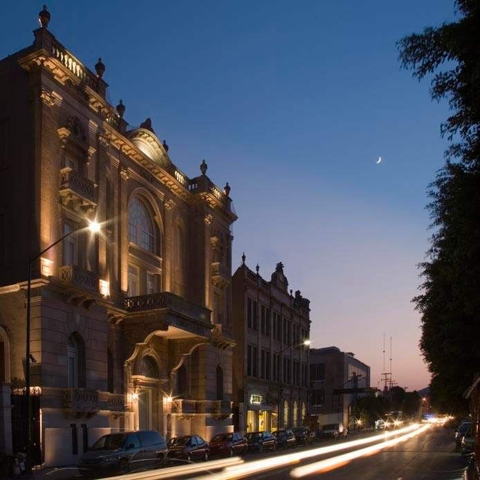 Grand historic building lit up at night near Camino Real Pedregal Mexico, with long exposure car light trails