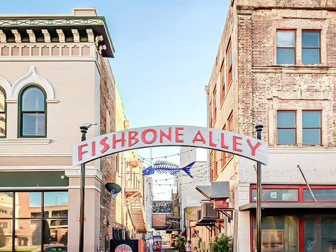 Entrance to Fishbone Alley featuring a hanging metal fish sculpture between buildings near The Markham Hotel