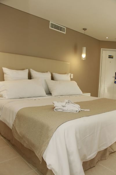 Cómoda Junior Suite del Country International Hotel con cama grande y albornoz blanco cuidadosamente doblado