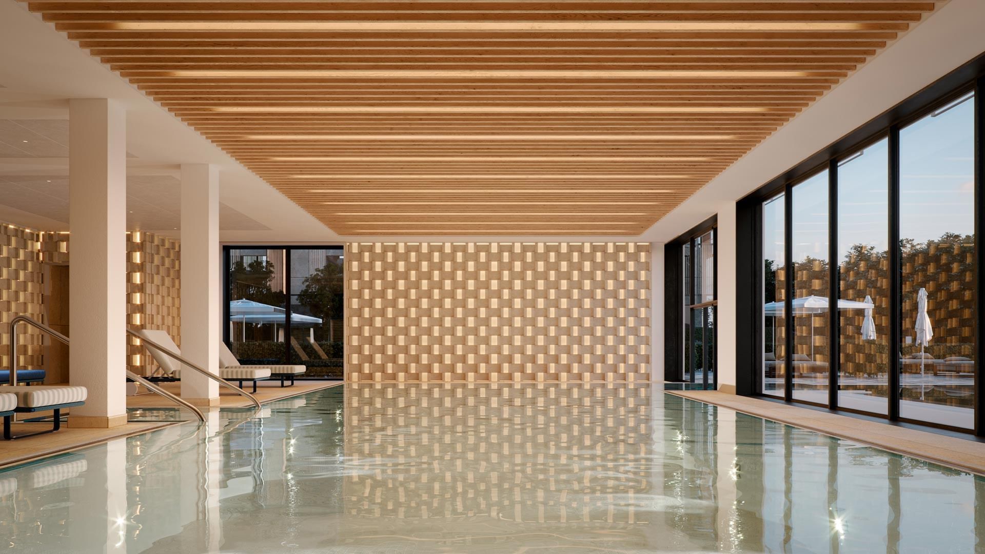 Indoor pool with wooden ceiling and walls, lounge chairs, and large glass windows showing outdoor patio.