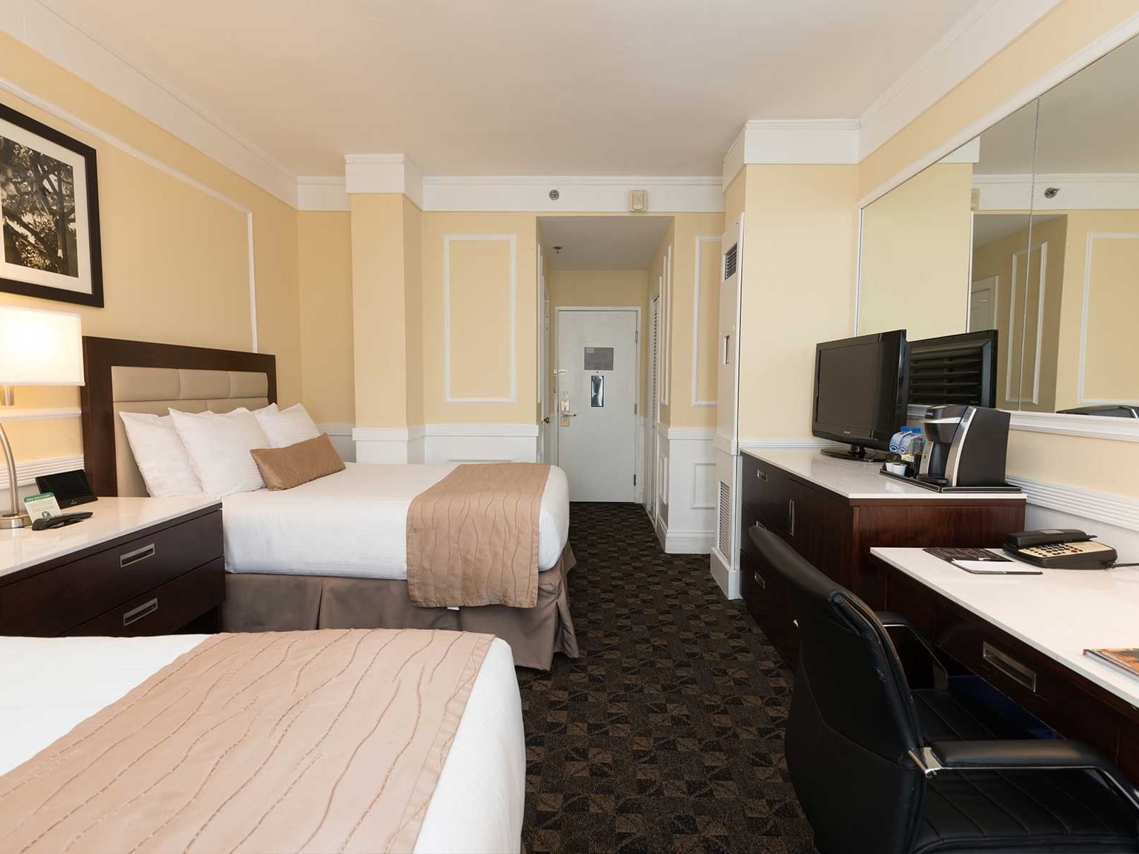 Two beds, desk, and large mirror in a hotel room at Pickwick San Francisco.