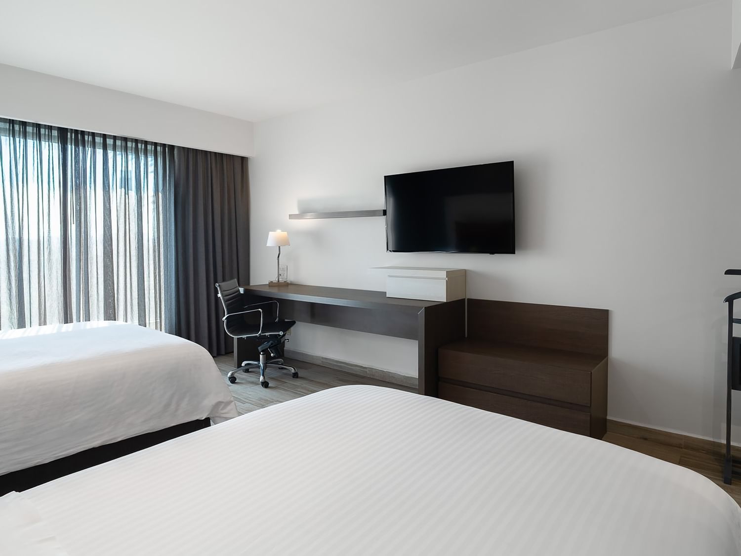 Habitación lujosa con dos camas dobles, escritorio y televisión en Real Inn Perinorte Tlalnepantla.