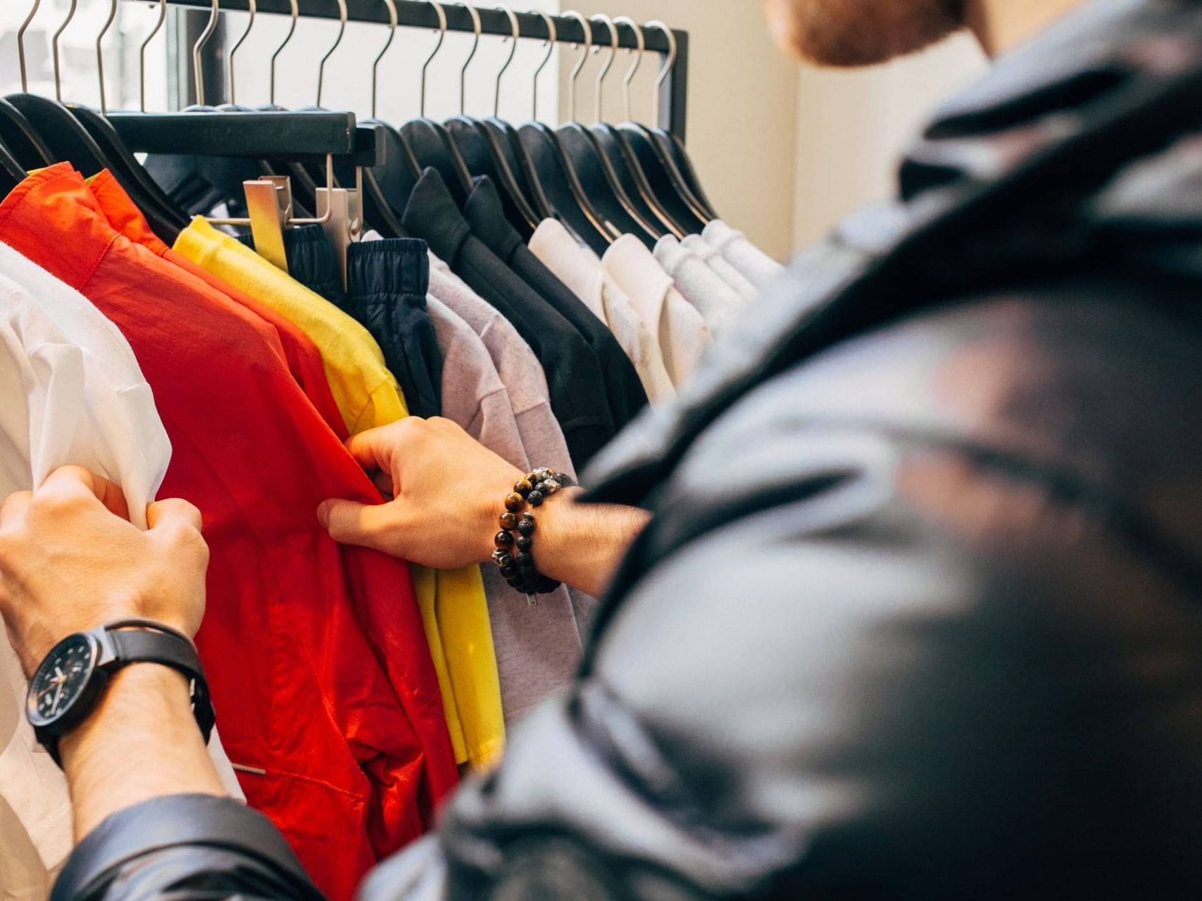 a man looking through shirts on a rack