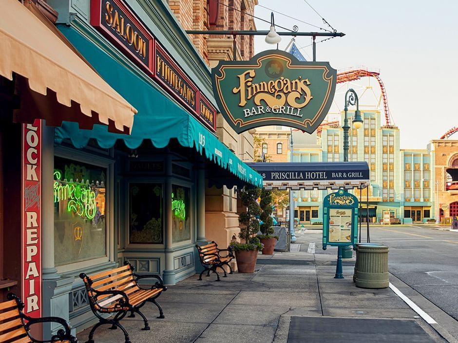 A side sreet view showin a green, yellow, and white hanging sign that says Finnegan's Bar & Grill, located in Universal Orlando Resort. 