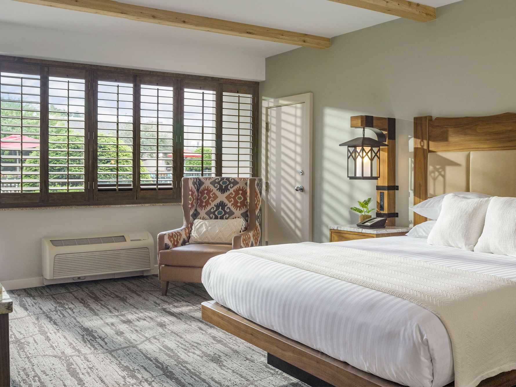 Hotel bedroom with king size bed and arm chair.