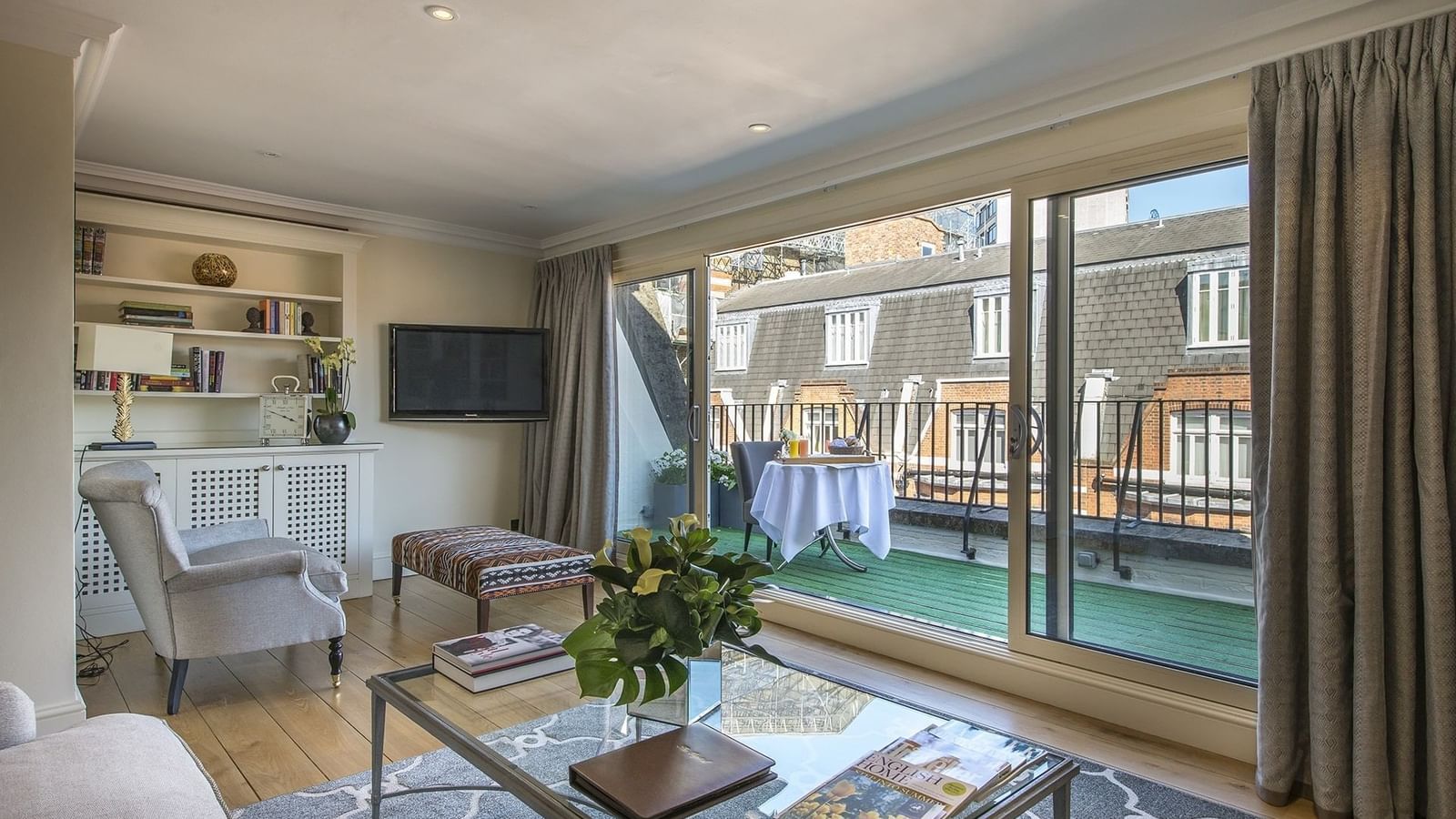 Penthouse with an armchair by coffee table & glass doors opening to a balcony at The Capital Hotel, Apartments and Townhouse