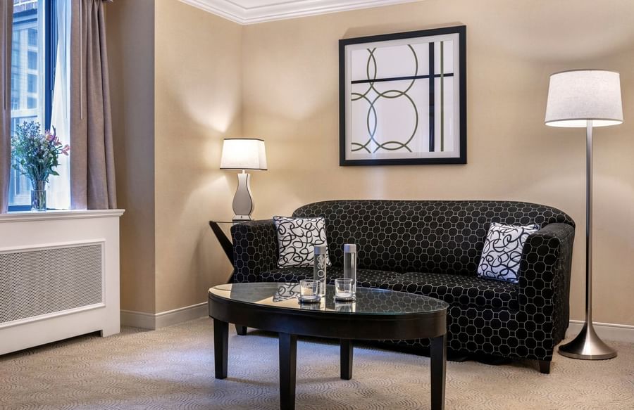 Black pattern sofa near floor lamp and haging wall art in Premium Suite Two Queen Beds at Warwick Allerton Chicago