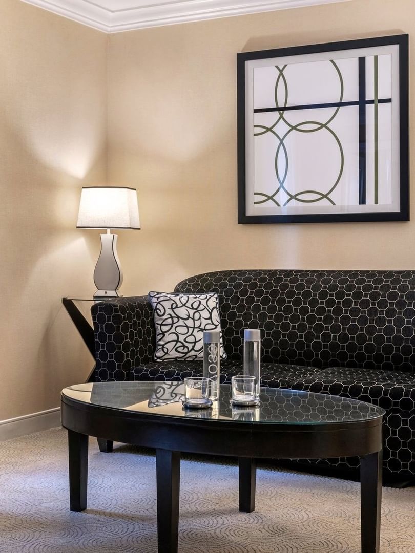 Black pattern sofa near floor lamp and hanging wall art in Premium Suite Two Queen Beds at Warwick Allerton Chicago